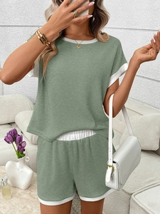 Detail of sage green ribbed knit lounge set showing contrast white trim on sleeve and hem