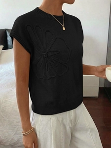 Dettaglio del ricamo floreale 3D su un gilet in maglia nera con trama delicata
