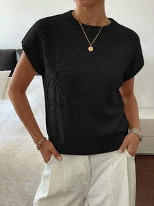 Dettaglio del ricamo floreale tridimensionale sul maglione nero in maglia senza maniche