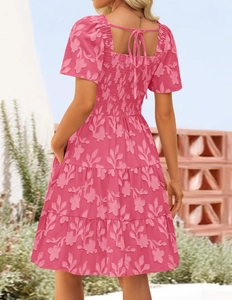 Detail of pink floral tiered dress featuring an open back with lace-up ties and smocking
