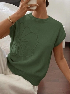 Dettaglio del gilet in maglia verde con ricamo floreale in rilievo e bordi a coste