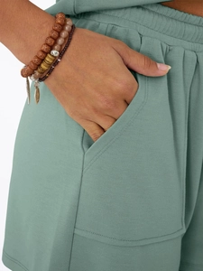 Detail of sage green lounge shorts showing side pockets and elastic waist texture