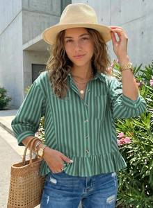 Detail of green striped shirt showing ruffle hem and button-down front in outdoor setting