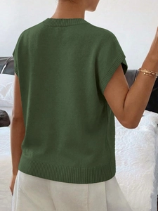 Dettaglio del gilet in maglia verde scuro con girocollo a costine e texture sul retro