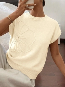 Dettaglio del maglione in maglia crema con applicazione floreale 3D e trama del tessuto