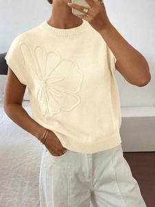 Dettaglio di un'applicazione floreale 3D su un gilet in maglia bianca con girocollo