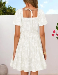 Detail of white floral embroidered dress with open back tie and smocked waist design