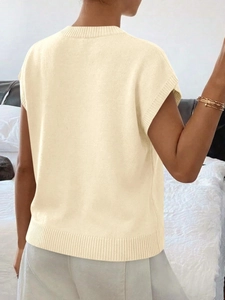 Dettaglio dei bordi a coste e della trama jacquard floreale di questo gilet in maglia crema