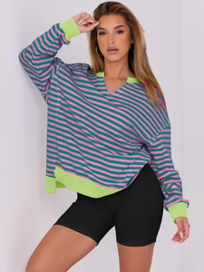 Detail of pink and green striped oversized sweatshirt featuring neon ribbed V-neckline