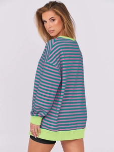 Detail of colorful striped sweatshirt showing oversized fit and ribbed green cuffs