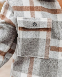 Detail of plaid flannel shirt jacket showing gray and brown checks with button pocket