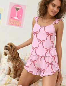 Detail of pink sleepwear set featuring red bow prints and ruffle hem straps on the camisole