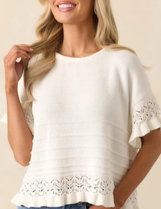 Detailansicht der weißen Strick-Kurzarmpullover mit Hohlspitze und Rüschendetails am Saum