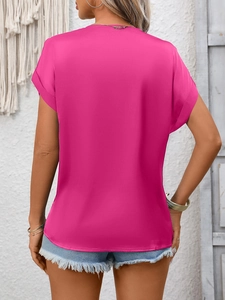 Detail view of bright pink satin blouse with rolled sleeves and curved hem on a model