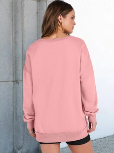 Rear view of pink drop-shoulder sweatshirt with ribbed cuffs and loose fit against grey wall