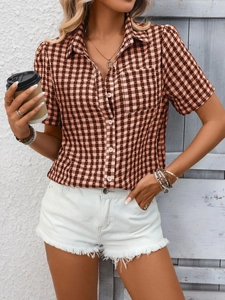 Détail d'une chemise à manches courtes à carreaux marron et blanc avec poche et col boutonné