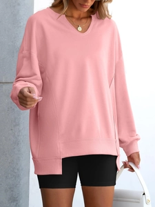 Close-up of pink oversized sweatshirt with V-neckline, side seam details, and split hem