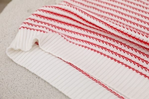 Macro shot of red and white wave knit texture and ribbed hem on the summer sweater