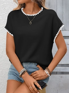 Dettaglio della maglia in maglia nera a maniche corte con bordo smerlato bianco e girocollo