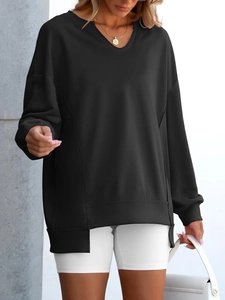 Detail of loose black v-neck sweatshirt showing side slits and ribbed cotton texture