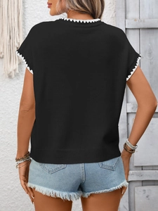 Dettaglio top in maglia nera con bordi smerlati bianchi su girocollo e maniche corte