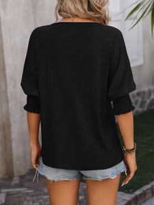 Detail of smocked sleeve cuffs and back seam on this loose black V-neck t-shirt