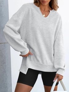 Detail view of light grey V-neck loose sweatshirt showing side split hem and rib knit cuffs
