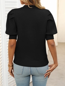 Close-up of elegant puff sleeve detail and ribbed cuffs on the black knitted top