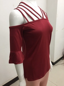 Detailed view of dark red off-shoulder top with cross-strap neckline and flared sleeves