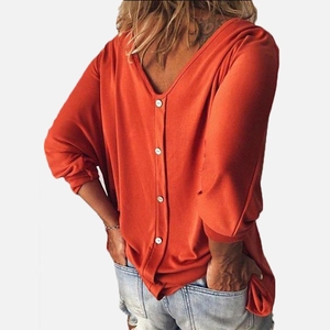 Detail view of brick orange V-neck top with white buttons on the back and denim shorts
