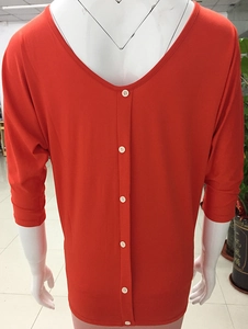 Detail view of the deep V-neck back with white buttons on an orange-red batwing sleeve top