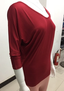 Detail view of the loose-fitting red batwing top featuring a wide round neckline