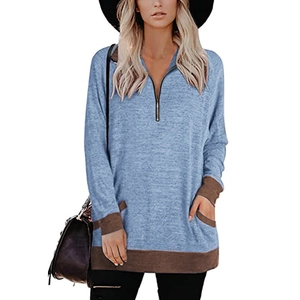 Détail du sweat-shirt bleu clair avec col V zippé et poches à bordures marron contrastées