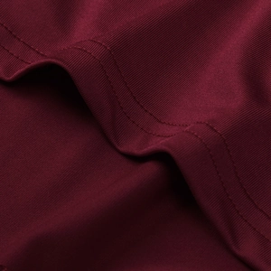 Detailed macro shot of dark red ribbed fabric with premium double-needle stitching quality