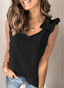 Détail d'un haut noir en mousseline à pois suisses avec un grand nœud d'épaule