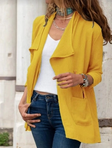 Détail d'un cardigan long jaune avec de grandes poches et un tissu texturé léger