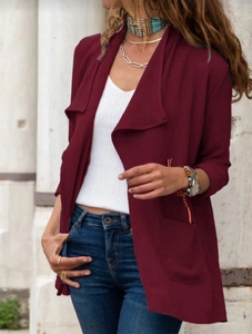 Détail d'un cardigan bordeaux texturé porté sur un débardeur blanc et un jean bleu