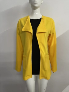 Détail du trench-coat jaune moutarde avec de larges revers et des poches symétriques