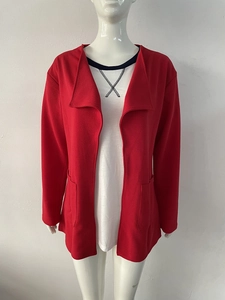 Détail d'un trench rouge à revers avec grandes poches et texture sur un mannequin blanc