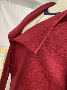 Détail du trench-coat bordeaux montrant le revers et le tissu texturé épais
