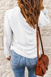 Detail of white waffle knit top showing intricate floral lace patchwork on sleeves