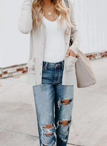 Close-up of beige ribbed knit cardigan with brown buttons and distressed blue jeans