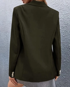 Detail view of the back of a dark olive green blazer with structured seams and gold cuff buttons
