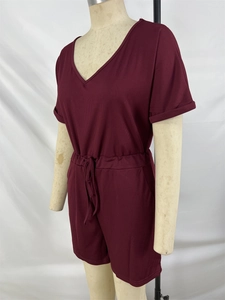 Detail of burgundy ribbed v-neck romper showing elastic waist and drawstring texture