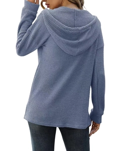 Détail de la maille gaufrée bleue sur un sweat à capuche ample avec poignets côtelés