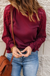 Detail of burgundy waffle knit texture and delicate lace patchwork on long sleeves