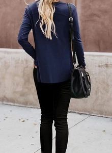 Outdoor shot of dark blue rib-knit cardigan showing loose fit and curved hem from back view