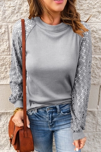 Detail of waffle knit fabric and geometric lace sleeve stitching on a grey top