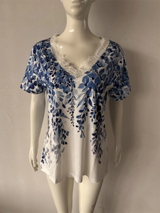 Dettaglio di stampa floreale blu e pizzo a ciglia bianco su top estivo con scollo a V
