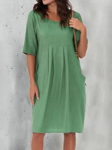 Detail of green cotton linen dress featuring side pockets and high waist pleats